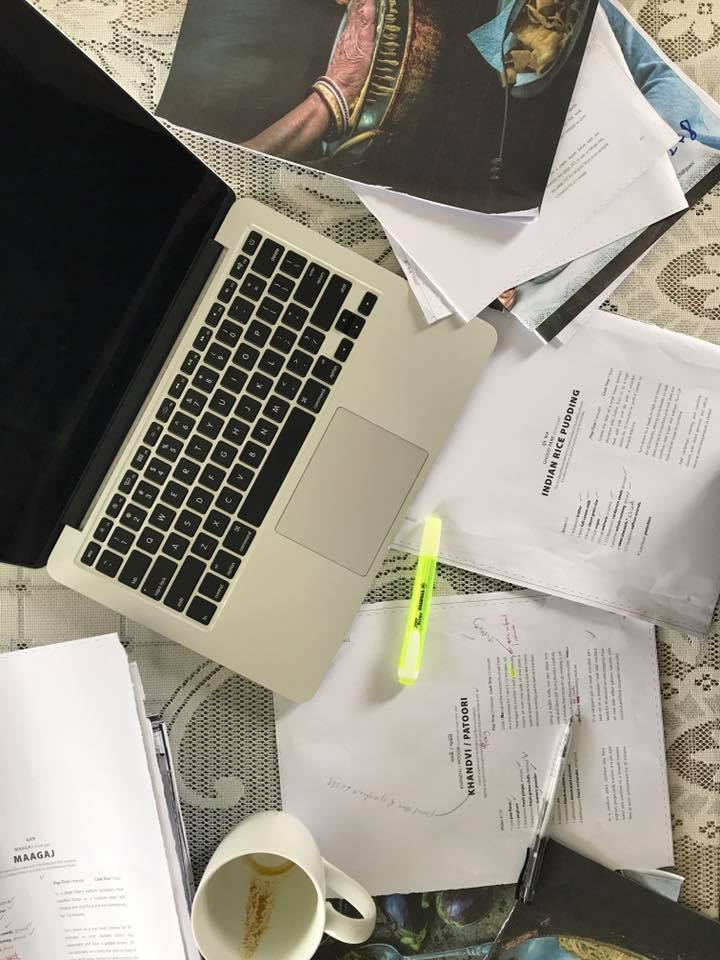 Working on cookbook, recipes drafts, highlighter, empty coffee cup