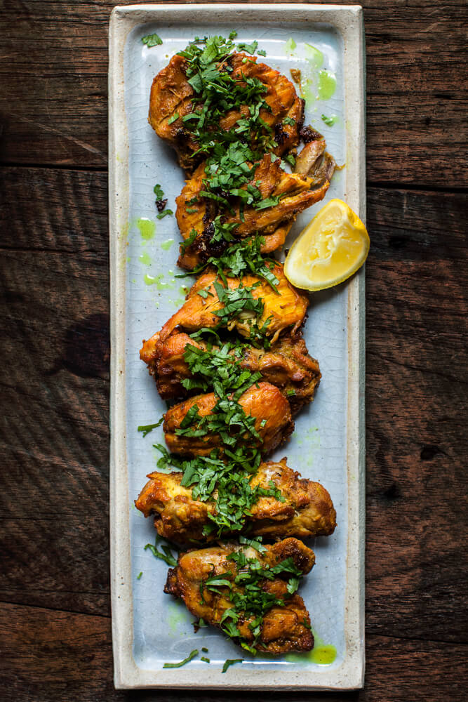 Gujarati fried masala chicken on a platter with coriander and lemon