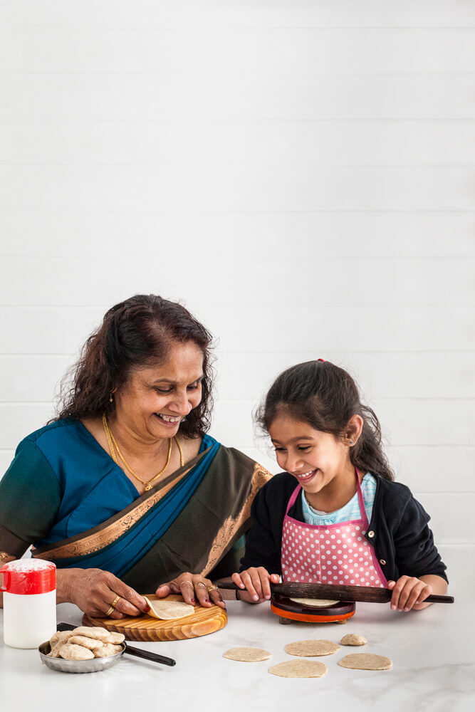Grandmother and granddaughter making rotli together in the kitchen